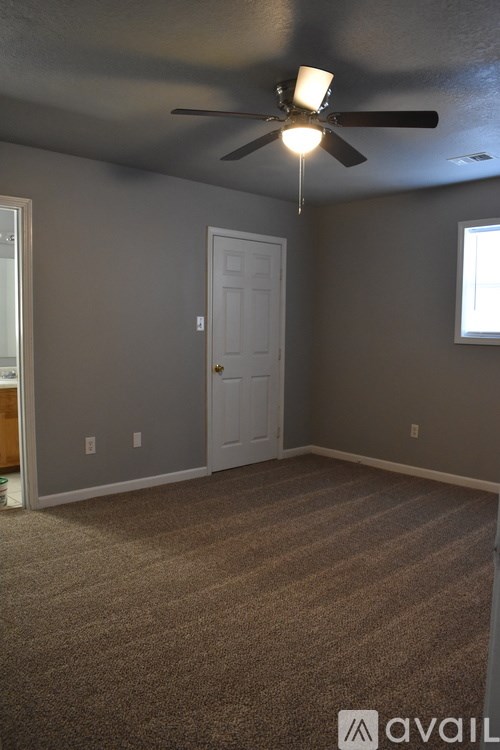 A room with a ceiling fan and carpeted floor.