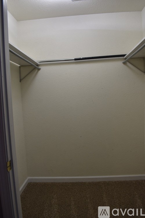 A small, empty room with a carpeted floor and a door on the left.