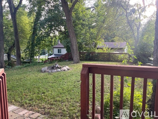 A small white building is surrounded by trees in a grassy area.