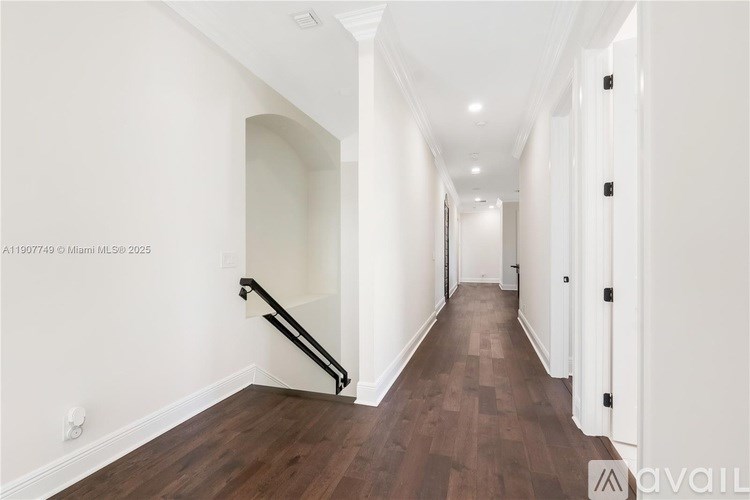 A long hallway with a wooden floor and white walls.