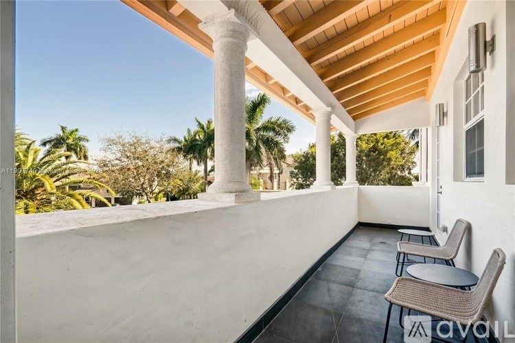 A balcony with a table and chairs overlooking a lush green landscape.