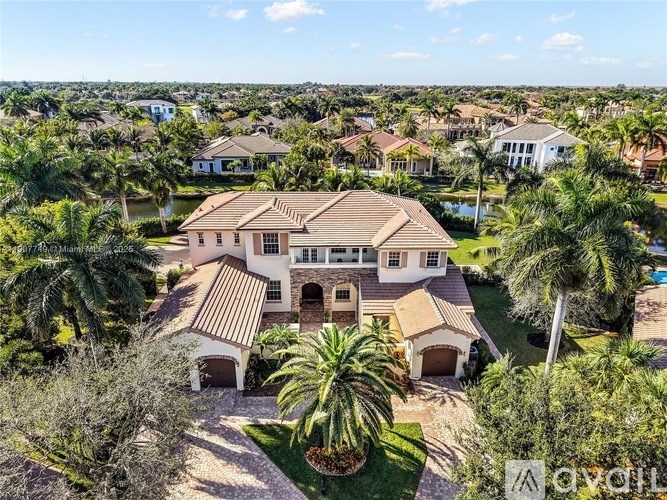 A large house with a driveway and palm trees in front.