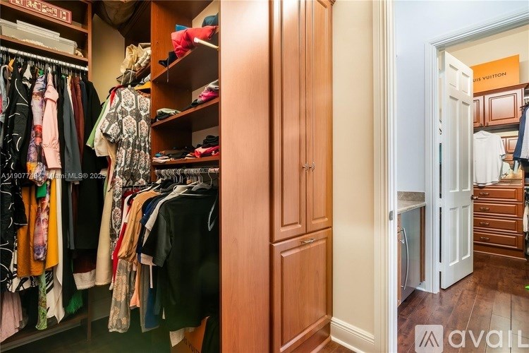 A room with a closet full of clothes and a doorway leading to another room.