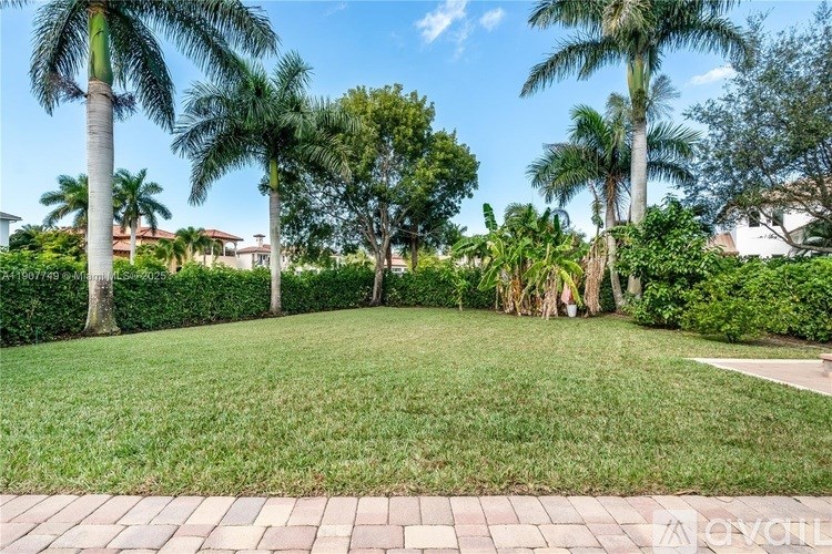 A well-maintained lawn with a brick pathway and several palm trees.