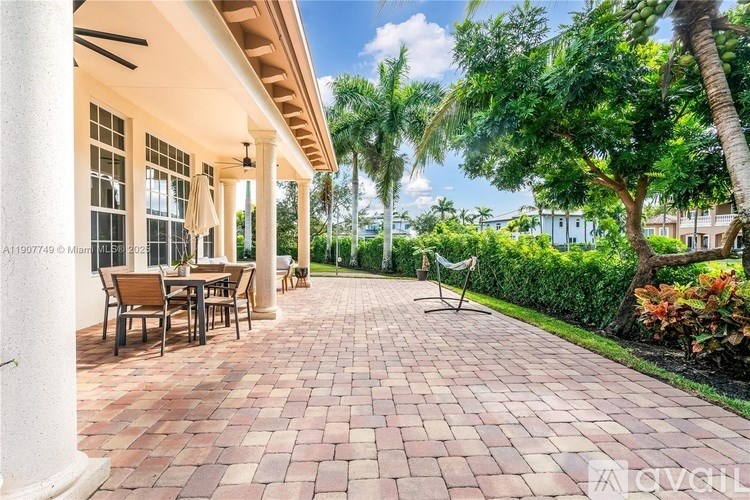 A patio with a table and chairs is surrounded by greenery.