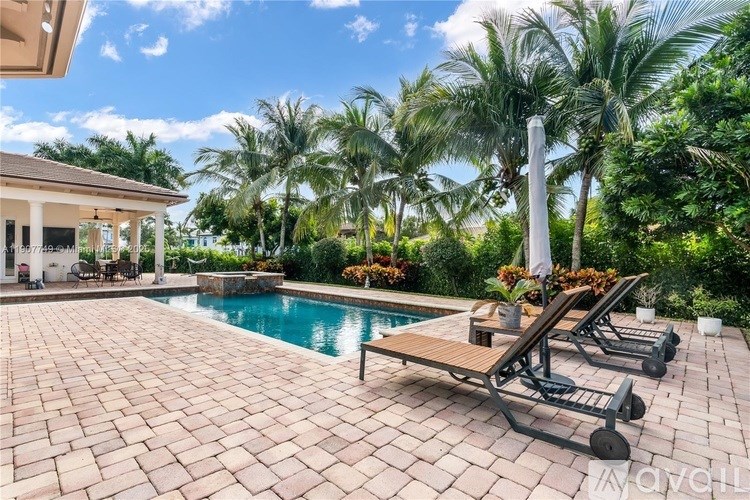 A pool surrounded by palm trees and deck chairs.
