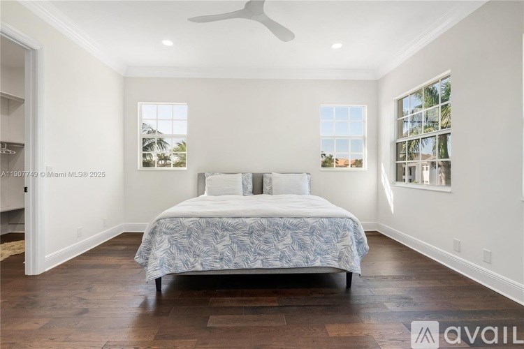 A bedroom with a bed, a ceiling fan, and a window.