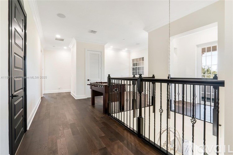 A long hallway with a black railing and wooden floors.