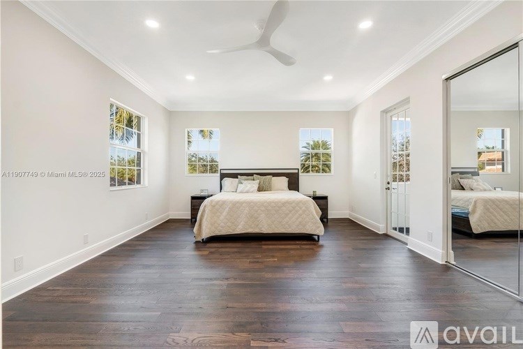 A bedroom with a bed, a ceiling fan, and a mirror.