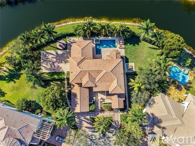 A bird's eye view of a house surrounded by a pool and greenery.