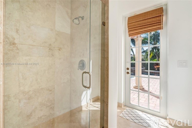 A bathroom with a walk-in shower and a door leading to a balcony.