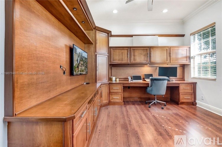 A home office with a wooden desk and a painting on the wall.