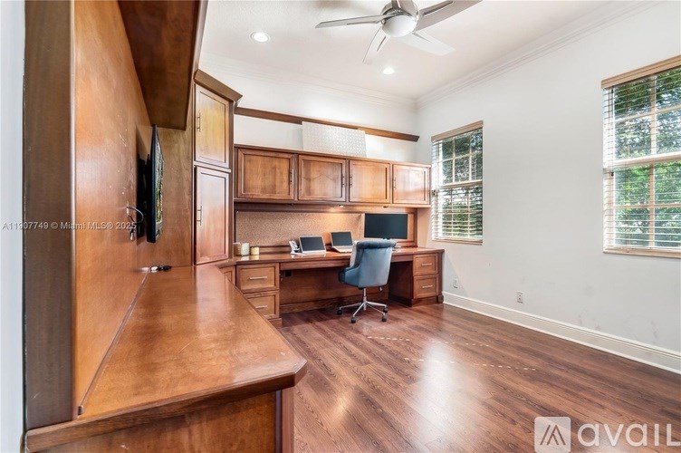 A home office with a desk, chair, and a television mounted on the wall.