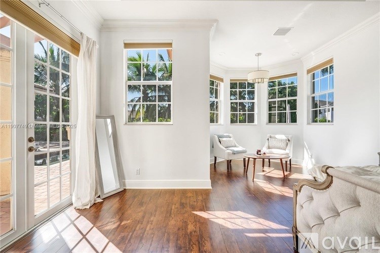 A bedroom with a large bed and a balcony with a view of trees.