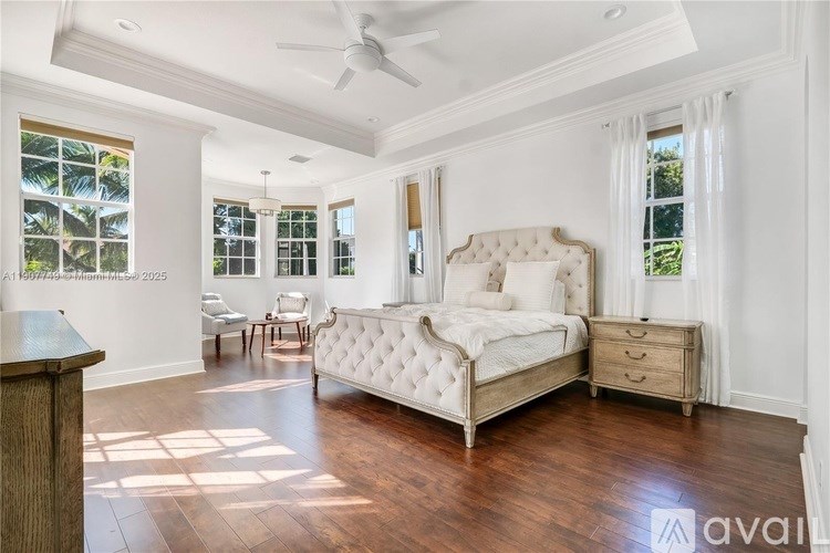 A bedroom with a large bed, a chair, and a ceiling fan.