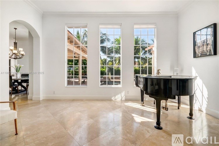 A grand piano sits in a spacious room with a view of a palm tree-lined street.