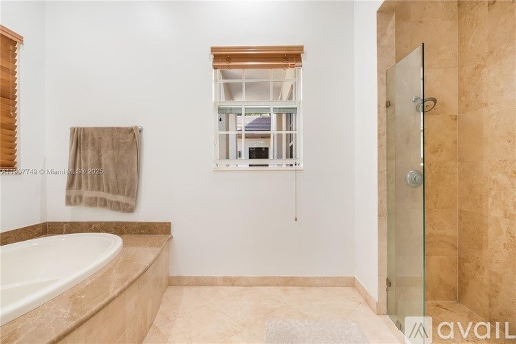 A bathroom with a tub, a window, and a glass shower door.