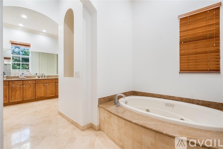 A bathroom with a tub and a window with blinds.