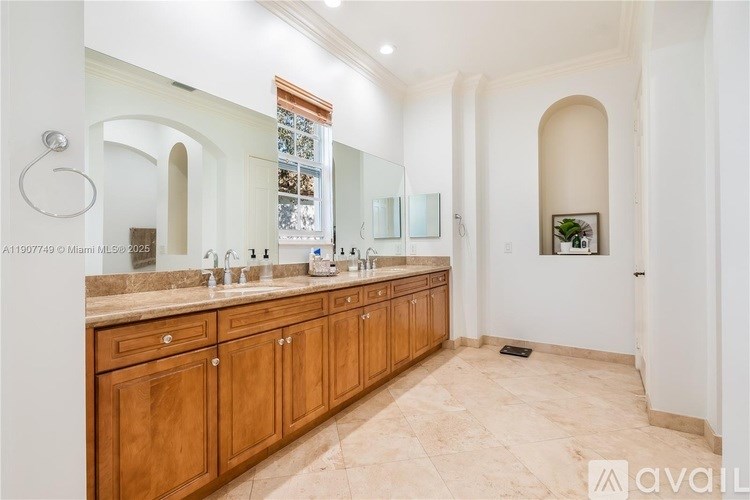 A bathroom with a large mirror, double sinks, and wooden cabinets.
