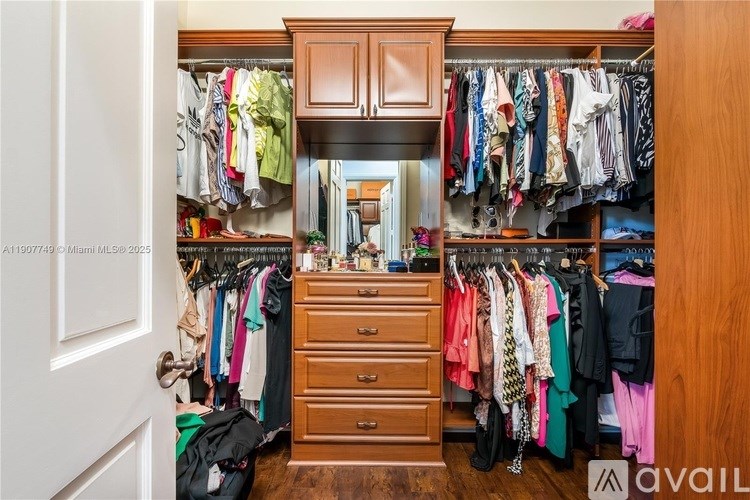 A wooden wardrobe with clothes hanging and drawers underneath.