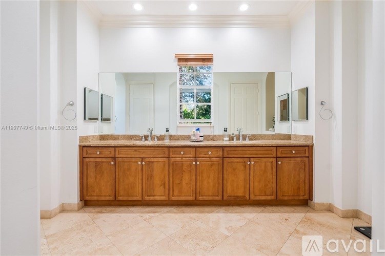 A bathroom with a large mirror and wooden cabinets.
