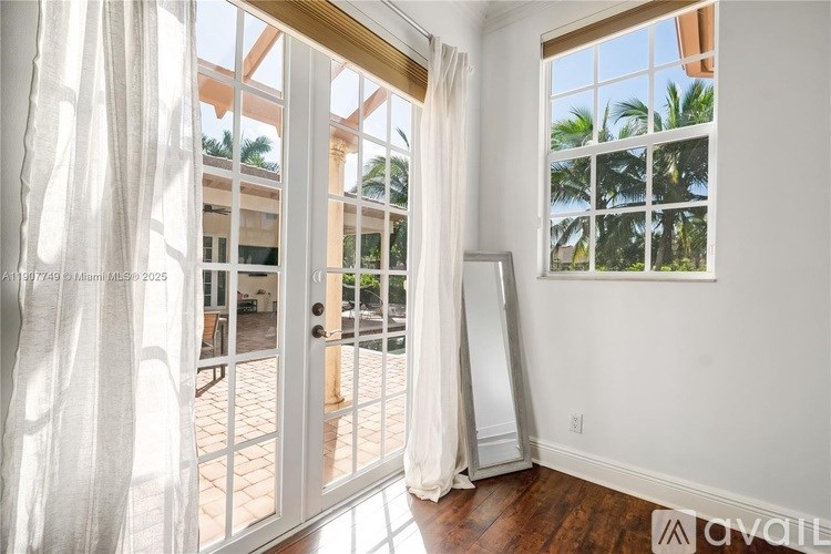 A room with a large window overlooking a patio with a door open to it.
