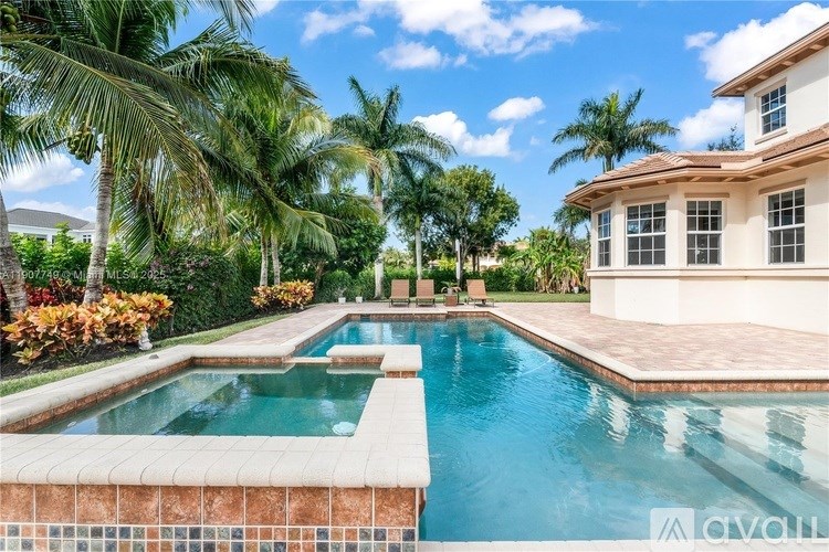 A pool surrounded by palm trees and a house.
