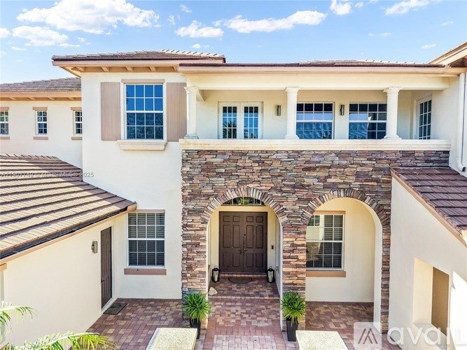 A house with a stone archway entrance and a brown roof.
