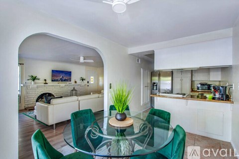 A modern living room with a glass table and green chairs.