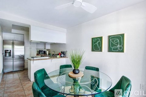 A modern kitchen with green chairs and a glass table.