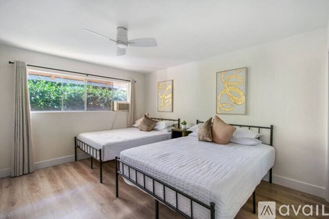 A bedroom with two beds and a ceiling fan.
