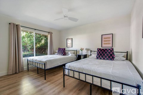 A bedroom with two beds and a ceiling fan.