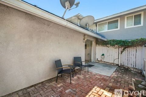 A patio with two chairs and a satellite dish on the roof.