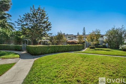 A well-maintained lawn with a pathway and a fence in the background.