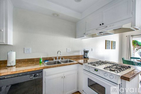 A kitchen with a white stove top oven and a white sink.