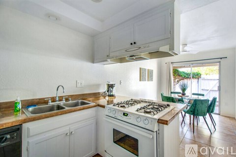 A kitchen with white cabinets and a white stove top oven.