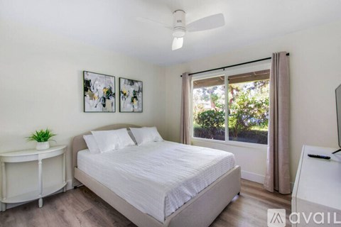 A bedroom with a bed, nightstand, and window with curtains.