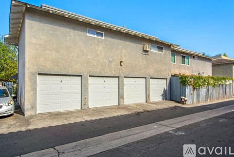 A two-story building with a garage door on the first floor and a balcony on the second floor.