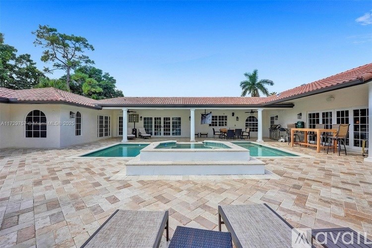 A large house with a pool in the middle of a tiled courtyard.