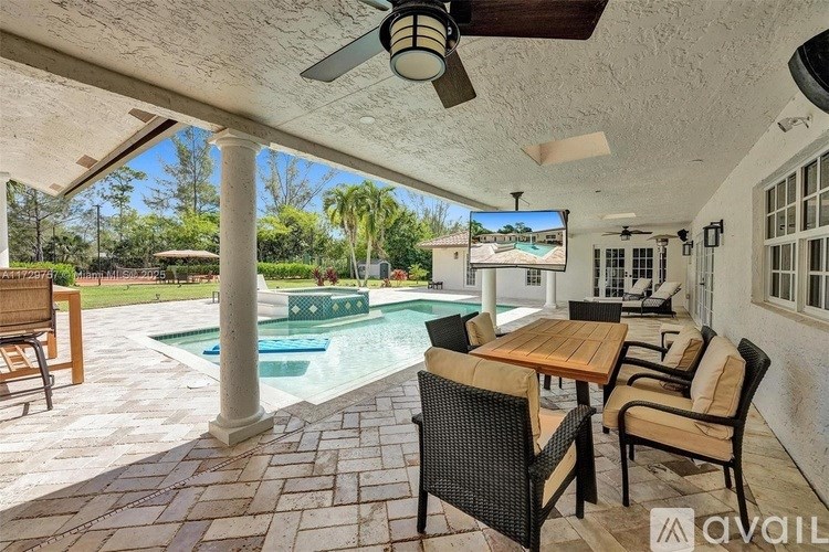 A patio with a table and chairs overlooking a pool.