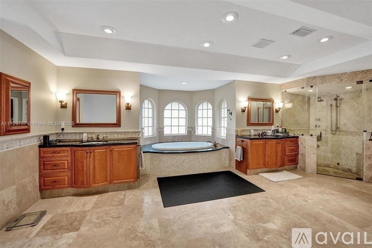 A large, well-lit bathroom with a bathtub, double sinks, and a large mirror.