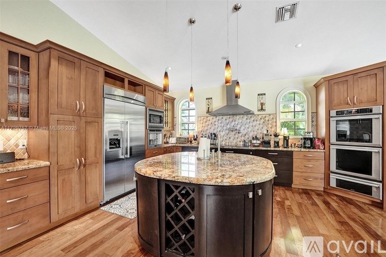 A kitchen with wooden cabinets and a marble island.