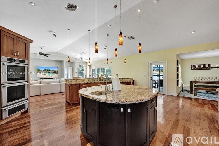 A kitchen with a center island and pendant lights.