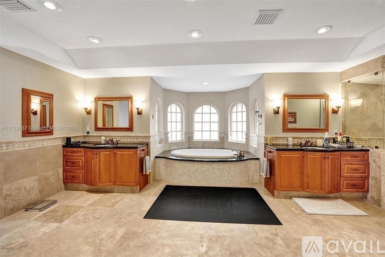 A large, well-lit bathroom with a bathtub, double sinks, and wooden cabinets.