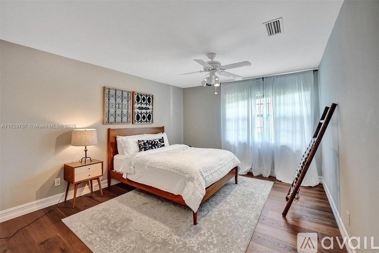 A bedroom with a bed, a ceiling fan, and a wooden floor.
