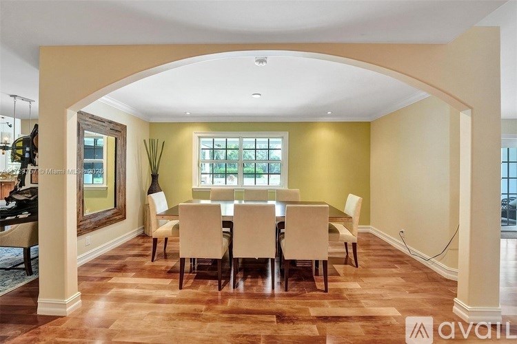 A dining room with a large table and chairs.