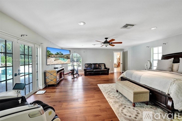 A spacious bedroom with a large bed and a flat screen TV mounted on the wall.