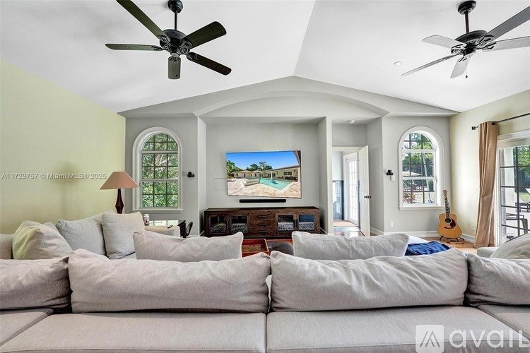 A living room with a large couch and a ceiling fan.