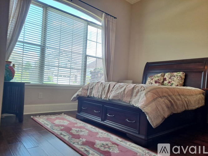 A bedroom with a large bed and a window with blinds.