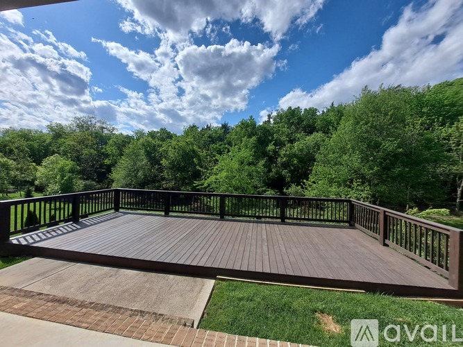 A deck with a railing and a view of the sky and trees.